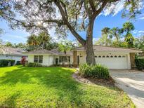 Charming single-story home with a lush green lawn, mature trees, and a two-car garage at 5708 Garden Lakes Fern, Bradenton, FL 34203