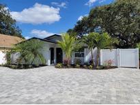 Charming single-story home featuring a beautifully landscaped front yard with a brick driveway, green plants, and a white fence at 1041 S Tuttle Ave, Sarasota, FL 34237
