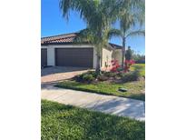 Charming single Gathering home featuring a barrel tile roof, brick paver driveway, and mature tropical landscaping at 12229 Amica Loop, Venice, FL 34293