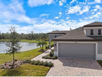 Beautiful exterior view of home with a three-car garage, landscaped yard, and serene pond in the backyard at 12518 Oak Hill Way, Parrish, FL 34219