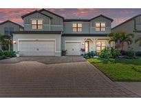 Two-story home featuring a three-car garage, brick driveway, and lush landscaping at 16438 Slate Pl, Lakewood Ranch, FL 34211