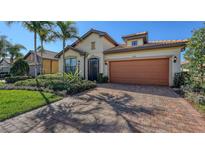 Charming home featuring a well-maintained lawn, beautiful landscaping, and a brick driveway at 17026 Loudon Pl, Bradenton, FL 34202