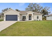 Charming one-story home with a well-maintained lawn, a blue garage door, and lovely landscaping at 8273 Givlic Ln, North Port, FL 34287