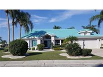 Charming single-story home featuring a turquoise tile roof, well-manicured landscaping, and an attached two-car garage at 1211 Peridot Lane, Sun City Center, FL 33573