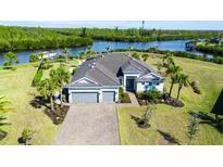 A beautiful waterfront home with a three-car garage and lush tropical landscaping at 14540 Gaspar Loop, Port Charlotte, FL 33981