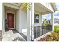 Inviting covered porch featuring a welcoming red front door and stylish gray-toned pavers at 44325 Saddlewood Ct, Punta Gorda, FL 33982
