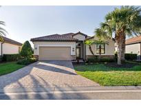 Charming single-story home featuring a tile roof, brick driveway, and lush landscaping at 6560 Willowshire Way, Bradenton, FL 34212