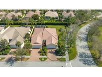 Expansive aerial view of a home with a red tile roof, lush landscaping, and a brick driveway at 7649 Quinto Dr, Sarasota, FL 34238