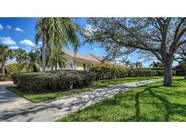 Charming home exterior featuring lush landscaping, a sidewalk, and mature trees under a partly cloudy sky at 7649 Quinto Dr, Sarasota, FL 34238