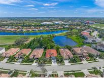 Stunning aerial view of the home in a lakeside community with lush greenery and a neighborhood pool at 8956 Stone Harbour Loop, Bradenton, FL 34212