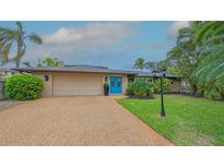 Charming home with a well-manicured lawn, lush landscaping, and a welcoming blue front door at 940 Siesta Key Pl, Sarasota, FL 34242