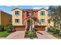 Mediterranean-style townhome with vibrant yellow and orange facade, tile roof, and two-car garage at 1308 3Rd Street E Cir, Palmetto, FL 34221
