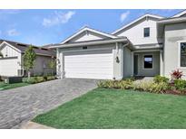 Charming home with a two-car garage, green lawn, and a beautifully paved driveway at 18821 Dayspring Pl, Venice, FL 34293
