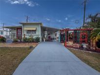 Charming home featuring a long driveway leading up to a red-doored home with colorful flowers and a trellis covered patio at 4103 12Th Street E Ct, Ellenton, FL 34222