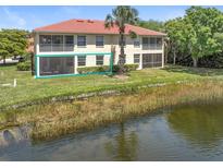 Waterfront property showcasing a screened lanai on the second level and a lush, tropical surrounding landscape at 602 Casa Del Lago Way # 602, Venice, FL 34292