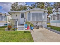 Charming manufactured home featuring a well-manicured lawn and a cozy front patio with chairs at 7 Brookshire Dr, Nokomis, FL 34275