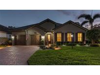 Charming single-story home with a manicured lawn and a brick driveway at dusk at 10406 Eastwood Dr, Bradenton, FL 34211