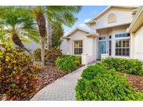 Landscaped front yard with lush greenery, a brick pathway, and a glimpse of the charming facade of the house at 12211 Lavender Loop, Bradenton, FL 34212