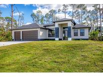 Beautiful single-story home featuring a three-car garage and a well-manicured lawn at 12495 Patsy Ave, Port Charlotte, FL 33981
