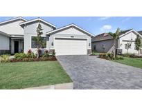 Charming single-Gathering home featuring a brick driveway, a two-car garage, and beautifully landscaped front yard at 18803 Dayspring Pl, Venice, FL 34293