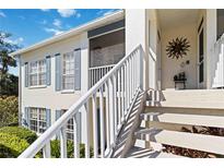 Two-story condo building showcasing white trim, sunny entryway, and charming blue shutters, creating a cozy, inviting appeal at 306 Lynbrook Cir # 201, Venice, FL 34292