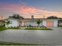 Charming single-story home with a white exterior, complemented by a colorful pink door and garage at 3228 Webber St, Sarasota, FL 34239