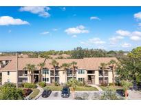 Beige two-story condo building featuring palm trees and a parking lot in a sunny, tropical setting at 4008 Crockers Lake Blvd # 13, Sarasota, FL 34238
