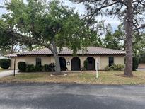 Charming single-story home featuring a red tile roof and mature trees in a well-manicured yard at 515 Rousseau Dr, Nokomis, FL 34275