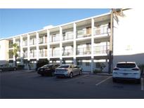Three-story condo building featuring white paint, balconies, and ample parking for residents and guests at 5889 Garden Ln # H4, Bradenton, FL 34207