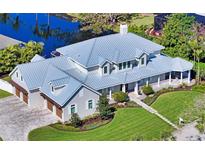 Stunning home with a metal roof, attached garage, manicured lawn, mature trees, and water view at 1543 Eastbrook Dr, Sarasota, FL 34231