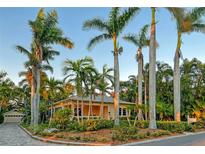 Charming yellow home surrounded by lush tropical landscaping and towering palm trees at 1631 Loma Linda St, Sarasota, FL 34239