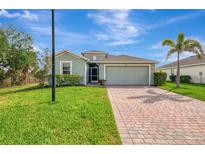 Charming one-story home with a brick driveway, two-car garage, and lush green lawn and landscaping at 3631 Pebble Ter, Punta Gorda, FL 33980