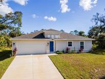 Charming one-story home featuring a neatly manicured lawn, a two-car garage, and a welcoming blue front door at 4757 Vaquero St, North Port, FL 34286