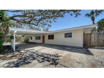 Charming single-story home featuring a covered carport, a bright red front door, and beautiful mature trees at 514 Ralph St, Sarasota, FL 34242