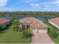 Beautiful waterfront home with lush landscaping, barrel tile roof and paver driveway at 8294 Barton Farms Blvd, Sarasota, FL 34240