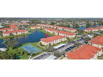 Beautiful aerial view of the condo complex with a tennis court, lake, and red-tiled roofs at 1005 Villagio Cir # 106, Sarasota, FL 34237