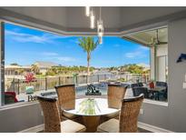 Dining area overlooking outdoor pool and waterfront view with clear, sun-filled skies, and comfortable seating at 360 Capri Isles Ct, Punta Gorda, FL 33950