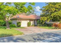 Charming single-story home featuring a red tile roof, brick driveway, and a well-maintained front lawn at 4920 Kestral Park Cir # 11, Sarasota, FL 34231