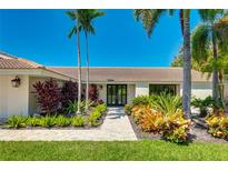 Charming single-story home featuring lush landscaping, a well-manicured lawn, and a welcoming double-door entrance at 526 Bird Key Dr, Sarasota, FL 34236