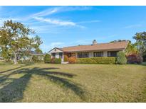 Charming single-story home featuring a well-manicured lawn, trimmed shrubbery, and a classic chimney, set beneath a bright blue sky at 1103 Palma Sola Blvd, Bradenton, FL 34209