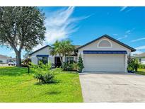 Charming single-story home with a well-manicured lawn, mature tree, and a two-car garage at 279 Park Forest Blvd, Englewood, FL 34223