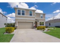 Well-manicured two-story home with a beige exterior, two-car garage, and landscaped front yard at 411 158Th E St, Bradenton, FL 34212