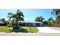 Charming single-story home featuring a well-manicured lawn and mature palm trees at 4414 Denice Ln, Sarasota, FL 34232