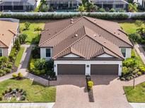 Stunning Mediterranean-style home with a tile roof, lush landscaping, and a brick paved driveway at 4721 Tortona Ct, Bradenton, FL 34211