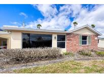 Single-story home with a tan exterior, red brick accent wall, and green shutters underneath a cloudy blue sky at 6140 Midnight Pass Rd # A10, Sarasota, FL 34242