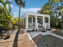 Charming home exterior with a welcoming white-railed front porch and tropical landscaping at 7119 Longboat E Dr, Longboat Key, FL 34228