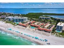 Beautiful aerial view of beachfront condos with private pool and beach access with blue umbrellas on white sand at 4621 Gulf Of Mexico Dr # 19B, Longboat Key, FL 34228
