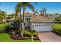 Beautiful single Gathering home featuring a tile roof, mature palm trees, and a well-manicured lawn at 7017 Lennox Pl, University Park, FL 34201