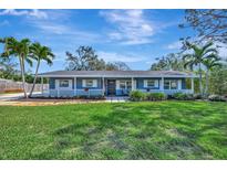 Charming home featuring a well-manicured lawn, picket fence, and lush palm trees adding curb appeal at 713 45Th W St, Bradenton, FL 34209