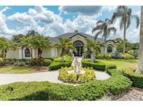 Stunning home exterior featuring lush landscaping, a circular driveway, and a beautiful water fountain at 10002 Cherry Hills Avenue Cir, Bradenton, FL 34202